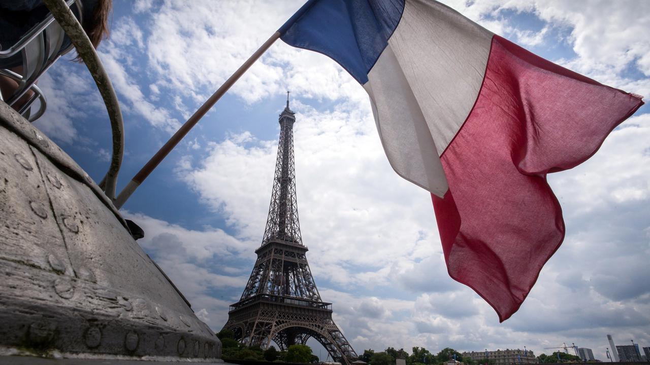 Die Flagge Frankreichs weht am Heck eines Schiffes vor dem Eiffelturm in Paris Die Flagge Frankreichs weht am Heck eines Schiffes vor dem Eiffelturm in Paris