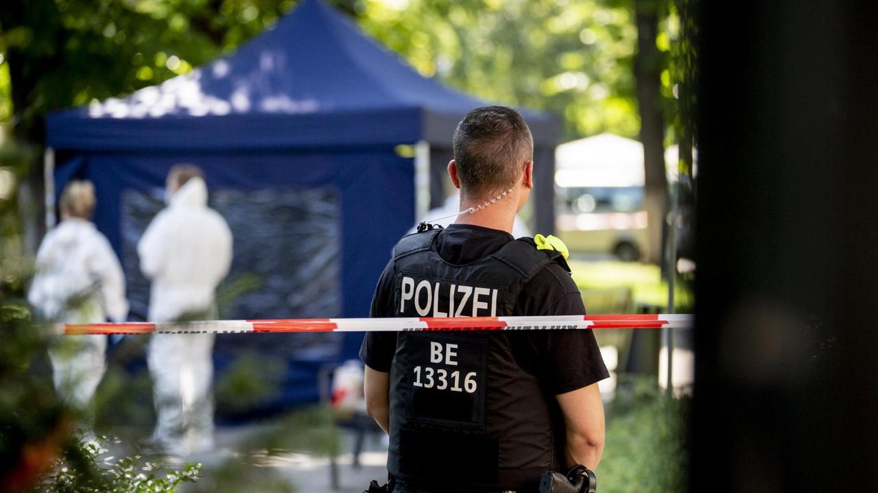 In einem Berliner Park sichert ein Polizeibeamter einen Tatort.