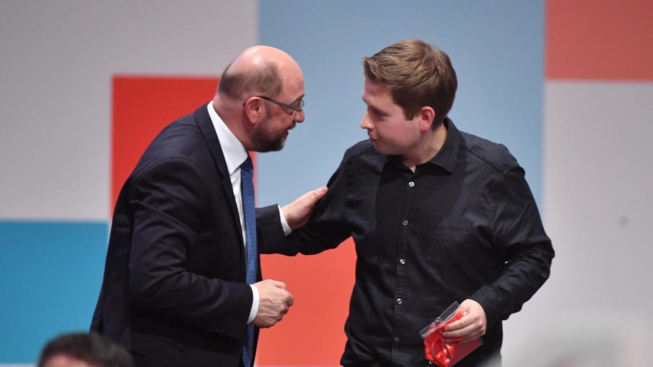 Der Juso-Vorsitzende Kevin Kühnert (r) gibt dem Parteivorsitzenden Martin Schulz die Hand nach den Abstimmungen über verschiedene Anträge zu Sondierungsgesprächen für eine große Koalition. Der Juso-Vorsitzende Kevin Kühnert (r) gibt dem Parteivorsitzenden Martin Schulz die Hand nach den Abstimmungen über verschiedene Anträge zu Sondierungsgesprächen für eine große Koalition.