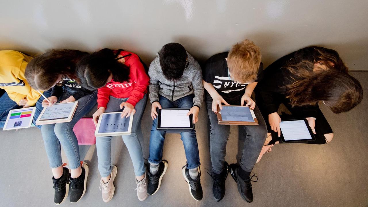 Schülerinnen und Schüler einer 7. Klasse lernen mit iPads im Matheunterricht an der Oberschule Gehrden in der Region Hannover. Mehrere Jugendliche sitzen auf dem Boden. Schülerinnen und Schüler einer 7. Klasse lernen mit iPads im Matheunterricht an der Oberschule Gehrden in der Region Hannover. Mehrere Jugendliche sitzen auf dem Boden.