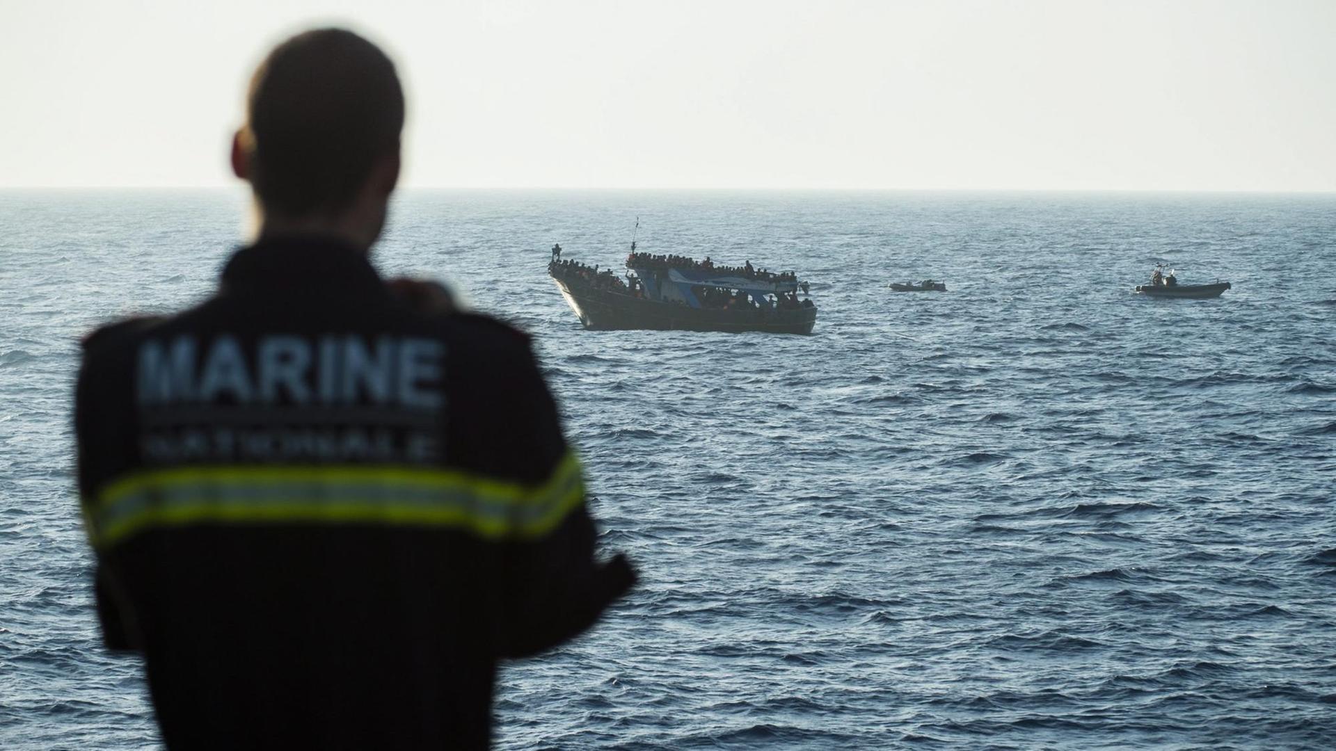 Ein Kommandeur der französischen Marine vor einem Boot mit Flüchtlingen während eines Frontex-Einsatz Ein Kommandeur der französischen Marine vor einem Boot mit Flüchtlingen während eines Frontex-Einsatz