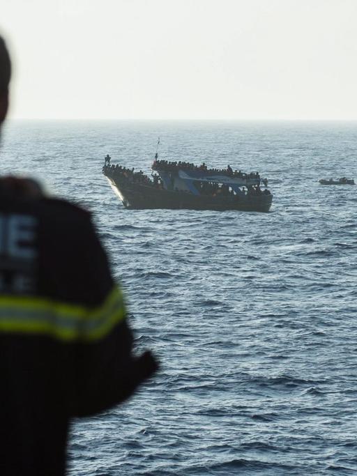 Ein Kommandeur der französischen Marine vor einem Boot mit Flüchtlingen während eines Frontex-Einsatz