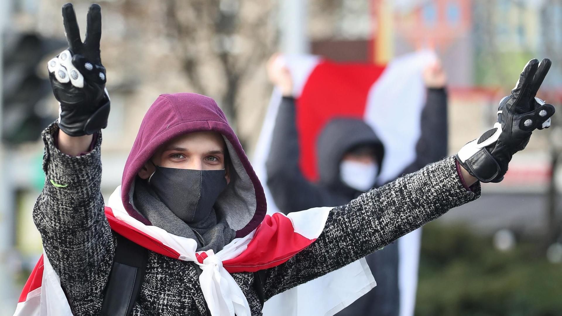 Ein junger Mann hat sich die rot-weiße Flagge als Cape umgebunden und formt mit beiden Händen ein Victory-Zeichen. Ein junger Mann hat sich die rot-weiße Flagge als Cape umgebunden und formt mit beiden Händen ein Victory-Zeichen.