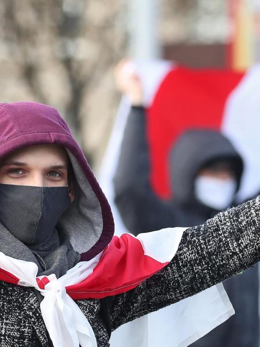 Ein junger Mann hat sich die rot-weiße Flagge als Cape umgebunden und formt mit beiden Händen ein Victory-Zeichen.