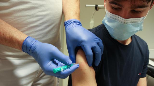 Ein Arzt setzt eine Corona-Schutzimpfung in den Oberarm