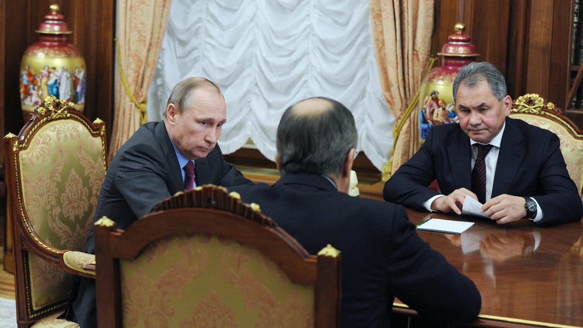 Russlands Präsident Wladimir Putin im Gespräch mit Außenminister Sergej Lawrow (m.) und Verteidigungsminister Sergej Shoygu (r.). Russlands Präsident Wladimir Putin im Gespräch mit Außenminister Sergej Lawrow (m.) und Verteidigungsminister Sergej Shoygu (r.).