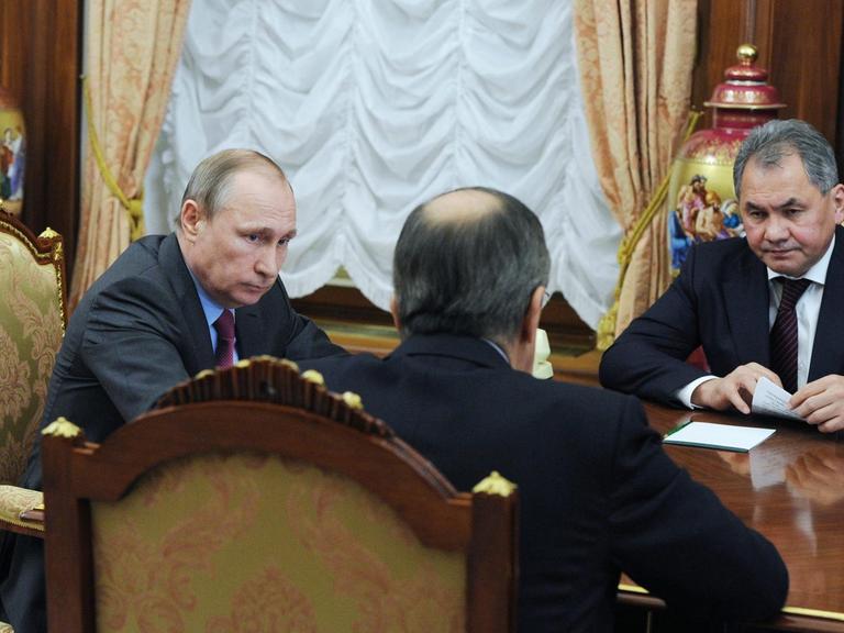 Russlands Präsident Wladimir Putin im Gespräch mit Außenminister Sergej Lawrow (m.) und Verteidigungsminister Sergej Shoygu (r.).