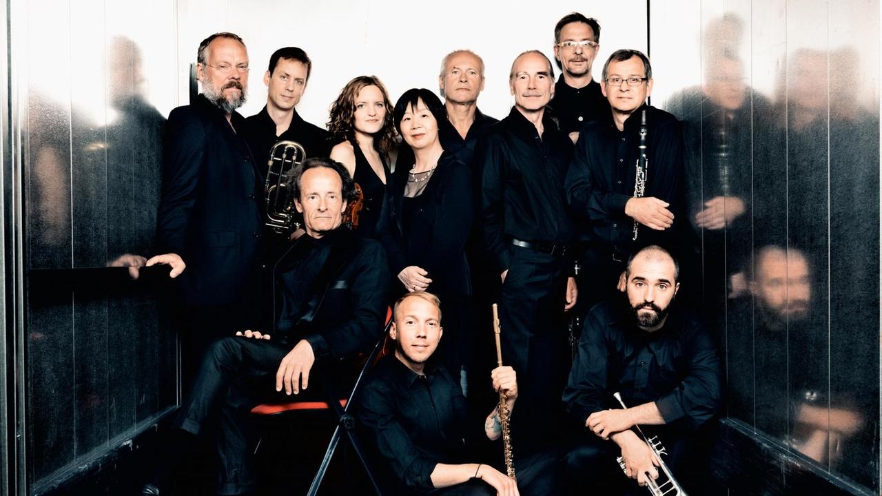 Die Mitglieder des Ensembles sitzen mit ihren Instrumenten eng beieinander. Die Mitglieder des Ensembles sitzen mit ihren Instrumenten eng beieinander.