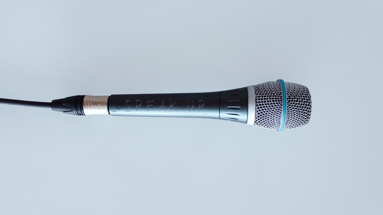 Ein Mikrofon vor grauem Hintergrund. Darauf eingeritz steht "Speak Up". Ein Mikrofon vor grauem Hintergrund. Darauf eingeritz steht "Speak Up".
