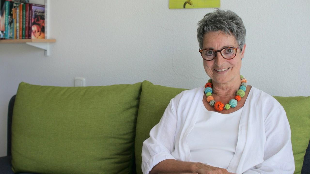 Barbara Küper, Agentin für Kinder- und Jugendliteratur in Frankfurt am Main sitzt auf einem grünen Sofa