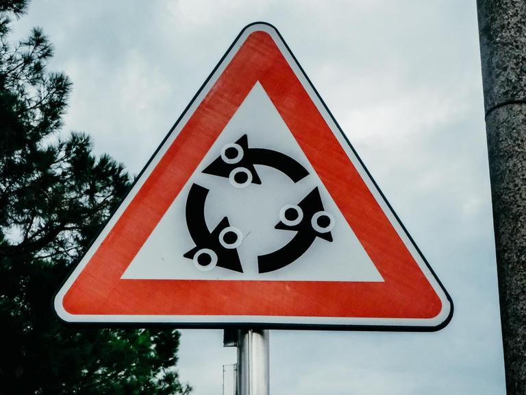 Ein Hinweisschild für einen Kreisverkehr, das mit Aufklebern verfremdet wurde.