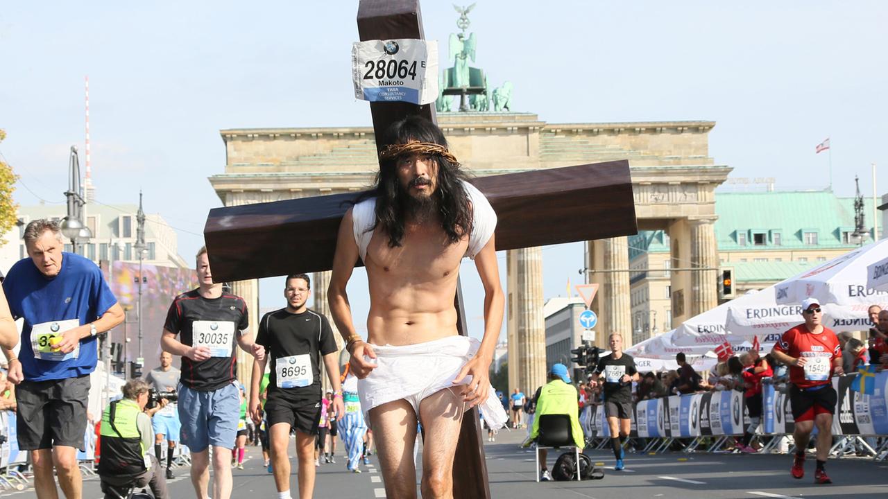 Ein Teilnehmer des Berlin-Marathons 2014 verkleidete sich als Jesus Christus, seine Teilnehmernummer hat er an sein Kreuz geheftet