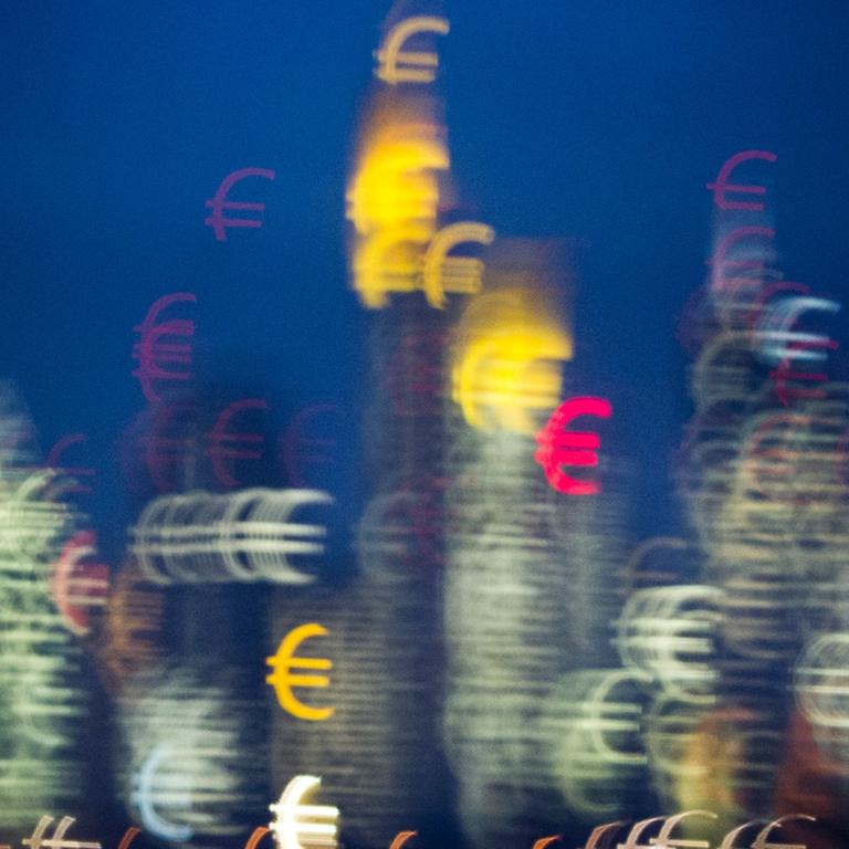 Die Bankentürme von Frankfurt am Main (Hessen) scheinen kurz nach Sonnenuntergang aus vielen kleinen Eurozeichen zu bestehen, aufgenommen am 31.01.2014. Der Effekt entsteht durch eine Schablone in Form eines Eurosymbols vor dem Objektiv.