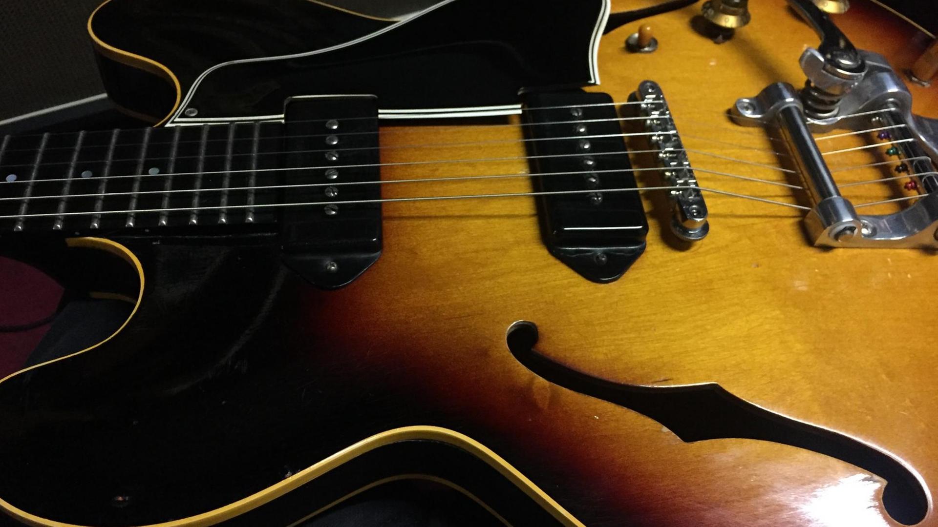 Eine schwarz-braune Gitarre liegt auf einem Tisch. Eine schwarz-braune Gitarre liegt auf einem Tisch.