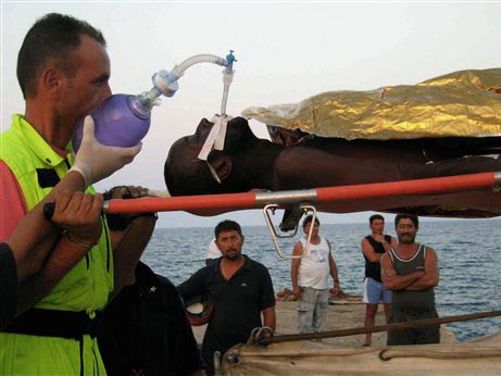 Helfer tragen auf Lampedusa einen afrikanischen Migranten von einem Schiff der italienischen Marine. Helfer tragen auf Lampedusa einen afrikanischen Migranten von einem Schiff der italienischen Marine.