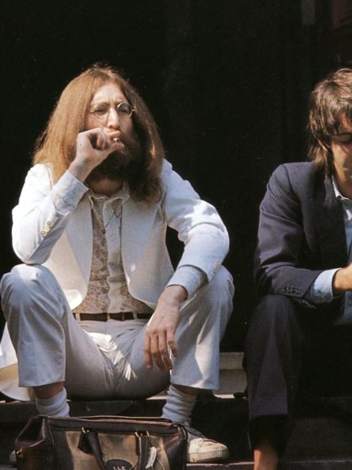 Die Beatles sitzen auf einer Treppe und gucken unverwandt in verschiedene Richtungen.