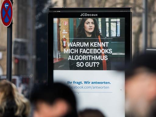 Menschen passieren im März 2018 in Köln ein Werbeplakat von Facebook mit dem Spruch "Warum kennt mich Facebooks Algorithmus so gut?".