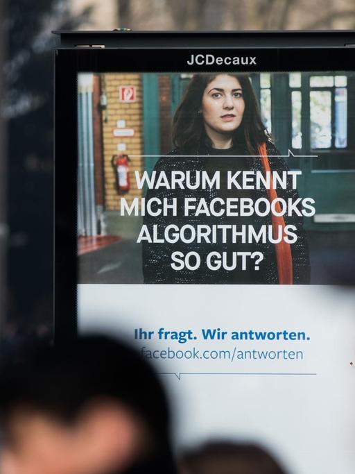 Menschen passieren im März 2018 in Köln ein Werbeplakat von Facebook mit dem Spruch "Warum kennt mich Facebooks Algorithmus so gut?".
