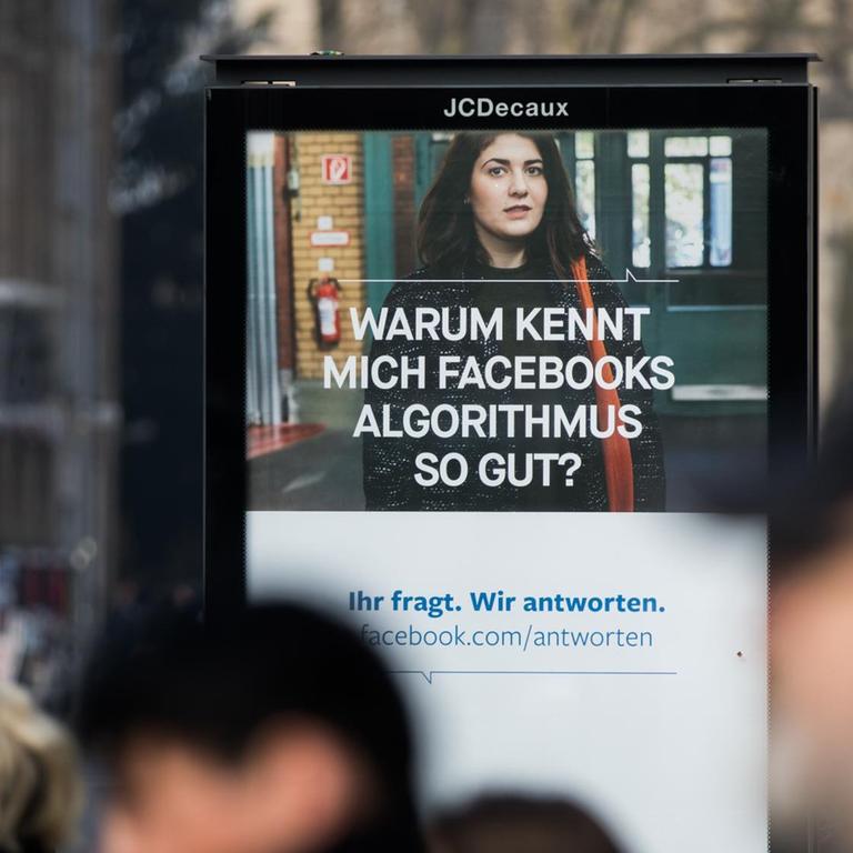 Menschen passieren im März 2018 in Köln ein Werbeplakat von Facebook mit dem Spruch "Warum kennt mich Facebooks Algorithmus so gut?".