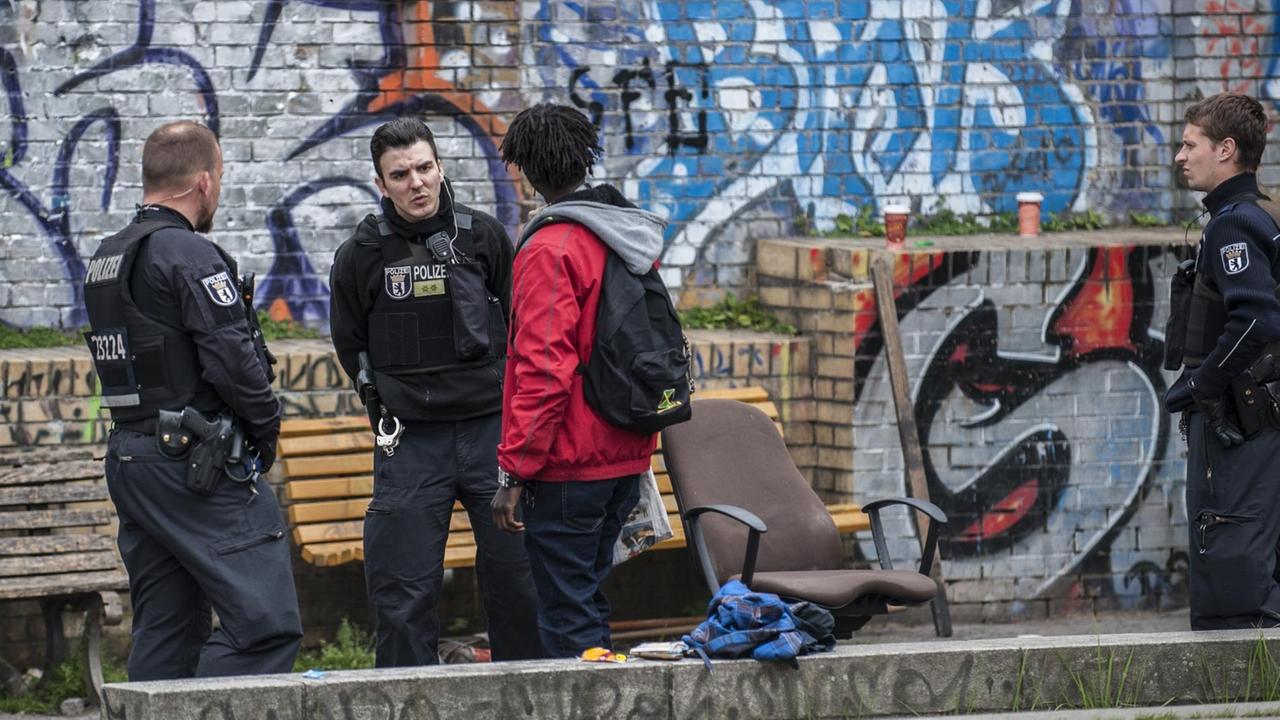 Die Grünanlage im Stadtteil Kreuzberg ist Treffpunkt für Drogendealer und Konsumenten. Polizisten kontrollieren einen Mann vor einer Mauer mit Graffitis