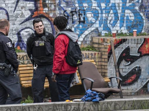 Die Grünanlage im Stadtteil Kreuzberg ist Treffpunkt für Drogendealer und Konsumenten. Polizisten kontrollieren einen Mann vor einer Mauer mit Graffitis