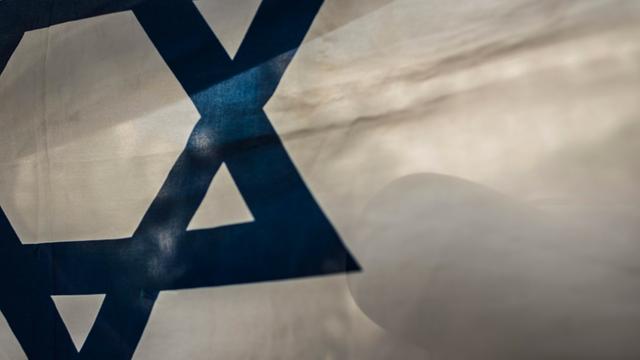 Auf der israelische Flagge spiegelt sich der Schatten einer Person