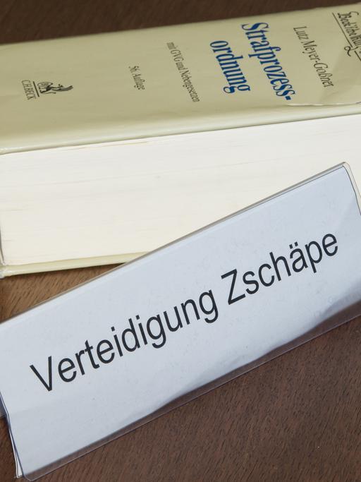Ein Schild mit der Aufschrift "Verteidigung Zschäpe" steht am 15.04.2014 auf der Anklageband im Gerichtssaal im Oberlandesgericht in München.