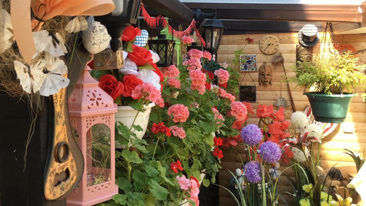 Eine mit Blumen und Leuchtmitteln bestückte Veranda Eine mit Blumen und Leuchtmitteln bestückte Veranda