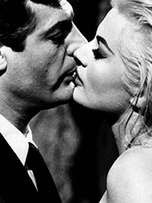Großaufnahme in Schwarzweiß von Marcello Mastroianni und Anita Ekberg, die in einem Stadtbrunnen stehen und sich küssen.