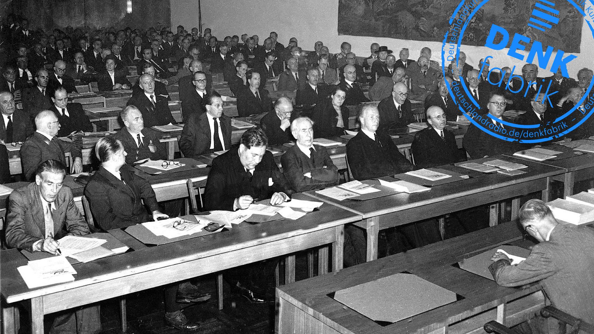 Erste Tagung des Parlamentarischen Rates am Nachmittag des 1. September 1948 in Bonn: Neben den 65 stimmberechtigten Mitgliedern aus westdeutschen Ländern nahmen Vertreter Berlins mit beratender Stimme an der Sitzung teil. In der ersten Reihe von links nach rechts: Max Reimann, KPD; Walter Menzel, SPD; Carlo Schmid, SPD; Theodor Heuss, FDP; Hans-Christoph Seebohm, DP; unbekannt; Adolf Suesterhenn, CDU; Anton Pfeiffer, CDU; Konrad Adenauer, CDU Erste Tagung des Parlamentarischen Rates am Nachmittag des 1. September 1948 in Bonn: Neben den 65 stimmberechtigten Mitgliedern aus westdeutschen Ländern nahmen Vertreter Berlins mit beratender Stimme an der Sitzung teil. In der ersten Reihe von links nach rechts: Max Reimann, KPD; Walter Menzel, SPD; Carlo Schmid, SPD; Theodor Heuss, FDP; Hans-Christoph Seebohm, DP; unbekannt; Adolf Suesterhenn, CDU; Anton Pfeiffer, CDU; Konrad Adenauer, CDU
