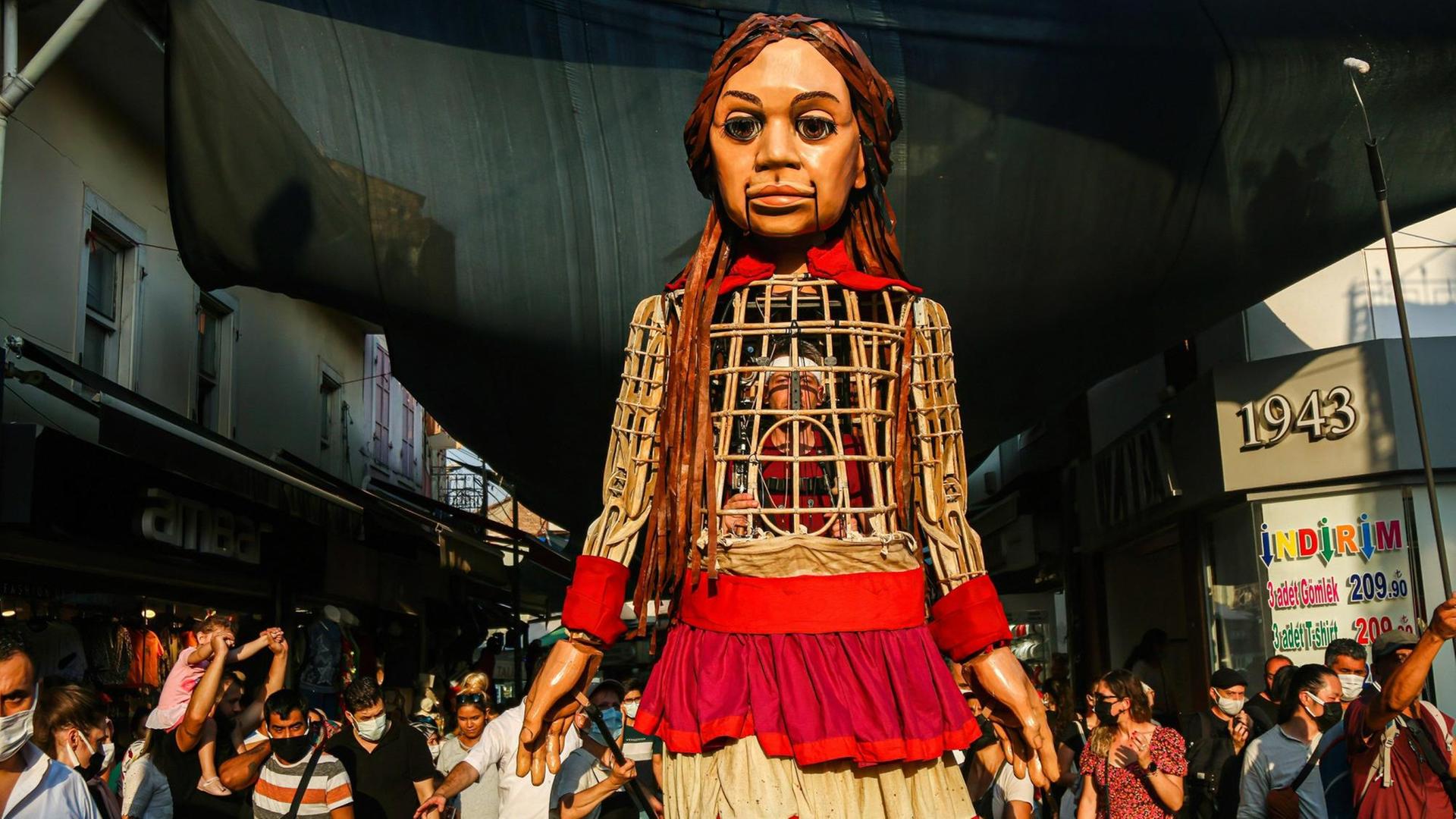 Die 3,5 Meter große Puppe "Amal" läuft durch die Straßen desr türkischen Stadt Izmir. Sie ist ein Teil der Kunstaktion "The Walk", in Gaziantepp gestartet und wird vier Monate lang 8.000 Kilometer gehen sowie acht Ländergrenzen der EU passieren. Dabei soll sie auf alle Herausforderungen aufmerksam machen, die syrische geflüchtete Kinder meistern müssen. Die 3,5 Meter große Puppe "Amal" läuft durch die Straßen desr türkischen Stadt Izmir. Sie ist ein Teil der Kunstaktion "The Walk", in Gaziantepp gestartet und wird vier Monate lang 8.000 Kilometer gehen sowie acht Ländergrenzen der EU passieren. Dabei soll sie auf alle Herausforderungen aufmerksam machen, die syrische geflüchtete Kinder meistern müssen.