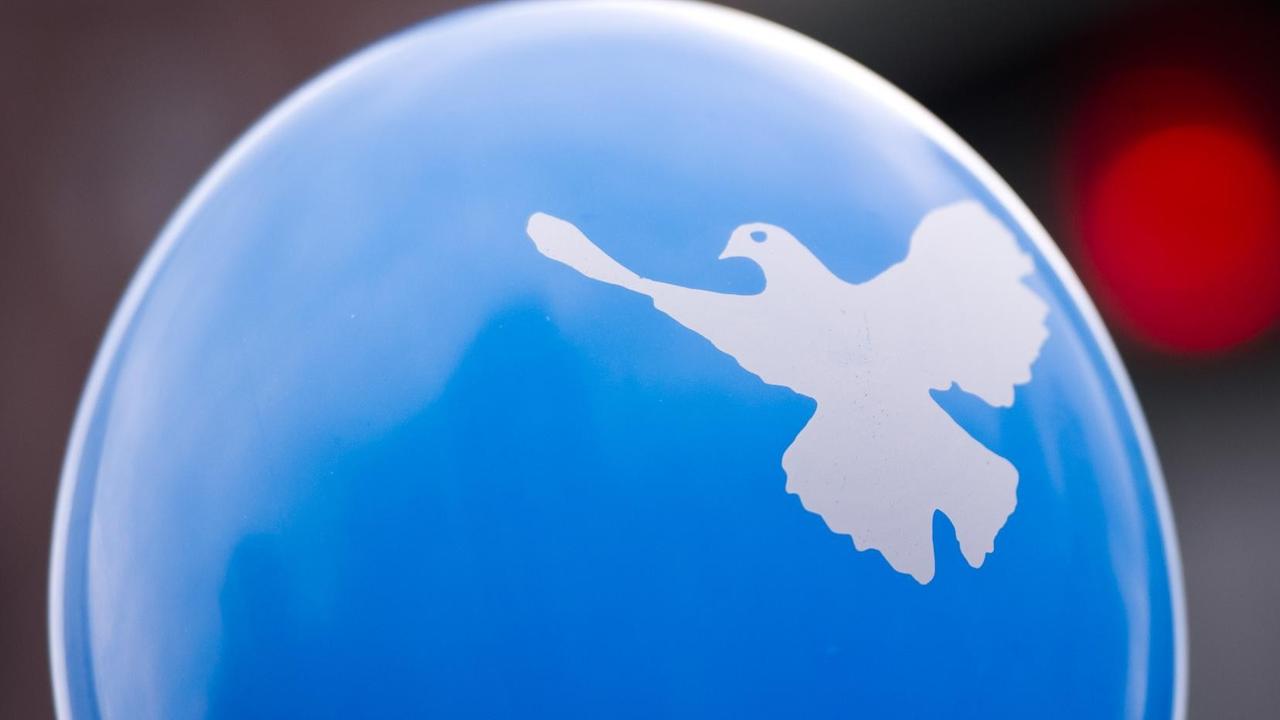 Ein Luftballon mit einer Friedenstaube ist während der Berliner Montagsdemo am 12.05.2014 vor einer roten Ampel zu sehen. Die Organisatoren und Demonstranten bei der Montagsdemo in Berlin fordern unter anderem globalen Frieden, Freiheit und Volkerverständigung. Foto: Daniel Naupold/dpa