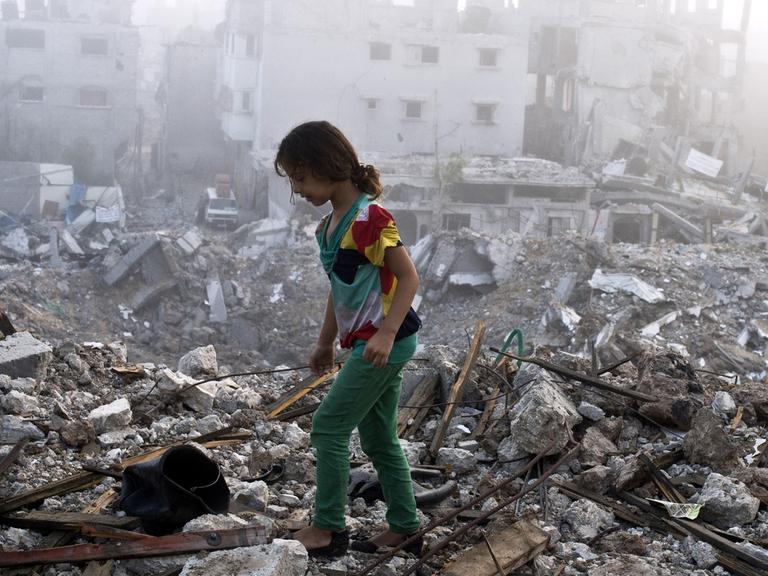 Ein Mädchen läuft über die Trümmer eines zerstörten Hauses.