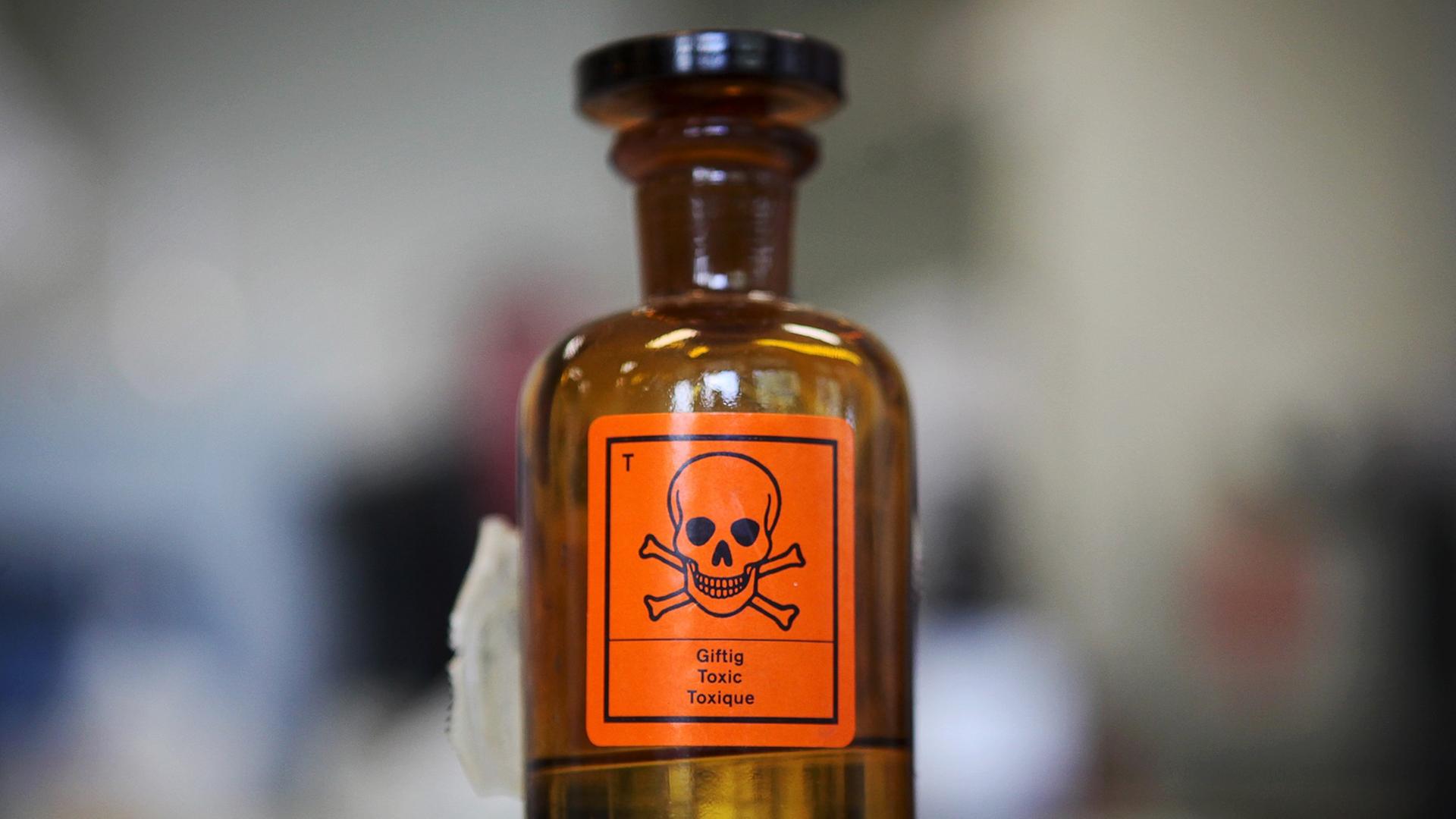Eine Chemieglasflasche mit einem Aufkleber für "giftig" und einem Totenkopf-Symbol Eine Chemieglasflasche mit einem Aufkleber für "giftig" und einem Totenkopf-Symbol