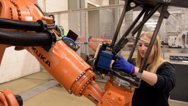 Mitarbeiterin beim Maschinenbauer KUKA mit einem Roboter Foto: Stefan Puchner/dpa | Verwendung weltweit