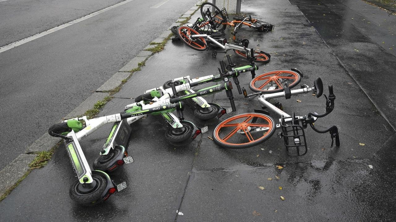 Auf einer Straße in Berlin liegen mehrere umgekippte Elektroroller und Leihräder. Auf einer Straße in Berlin liegen mehrere umgekippte Elektroroller und Leihräder.