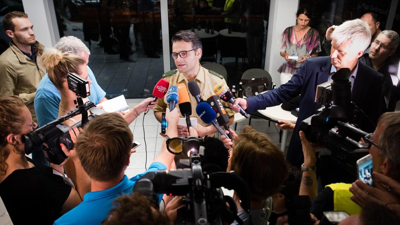Sie sehen Marcus da Gloria Martins, den Pressesprecher der Polizei München, auf den viele Mikrofone gerichtet sind. Sie sehen Marcus da Gloria Martins, den Pressesprecher der Polizei München, auf den viele Mikrofone gerichtet sind.