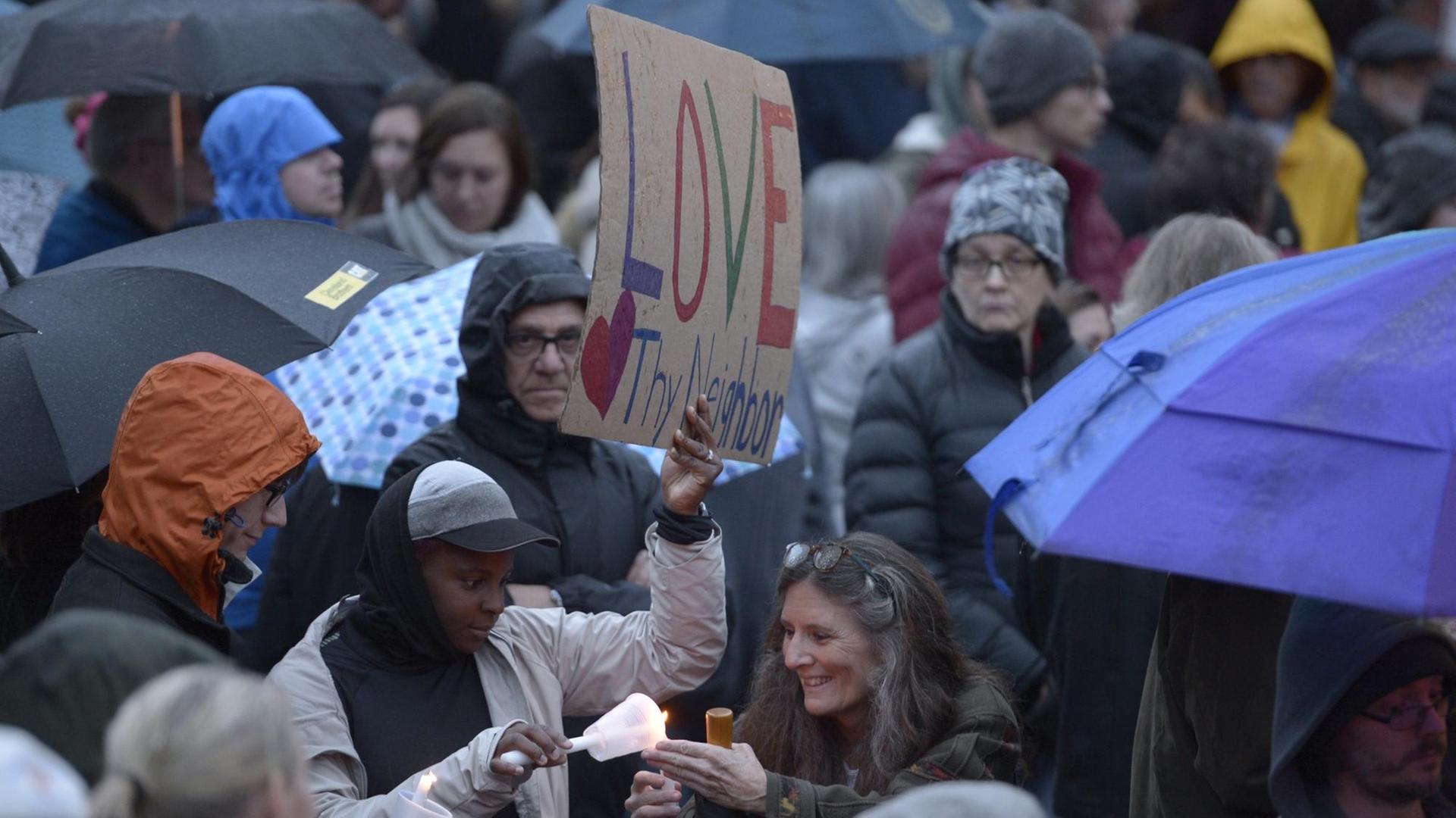 Eine Frau hilft einem anderen, eine Kerze anzuzünden, während Mitglieder der Squirrel Hill-Gemeinde für eine von Studenten organisierte Kerzen-Mahnwache zum Gedenken an diejenigen zusammenkommen, die früher am Tag bei einer Schießerei in der Tree of Life-Synagoge im Viertel Squirrel Hill in Pittsburgh gestorben sind Eine Frau hilft einem anderen, eine Kerze anzuzünden, während Mitglieder der Squirrel Hill-Gemeinde für eine von Studenten organisierte Kerzen-Mahnwache zum Gedenken an diejenigen zusammenkommen, die früher am Tag bei einer Schießerei in der Tree of Life-Synagoge im Viertel Squirrel Hill in Pittsburgh gestorben sind