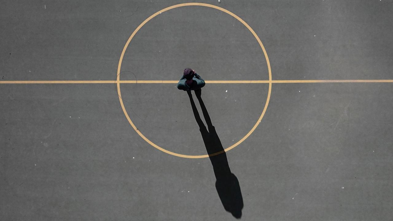 Ein Mann steht im Zentrum eines Spielfeldes, sein Schatten ragt aus dem...</p>

                        <a href=