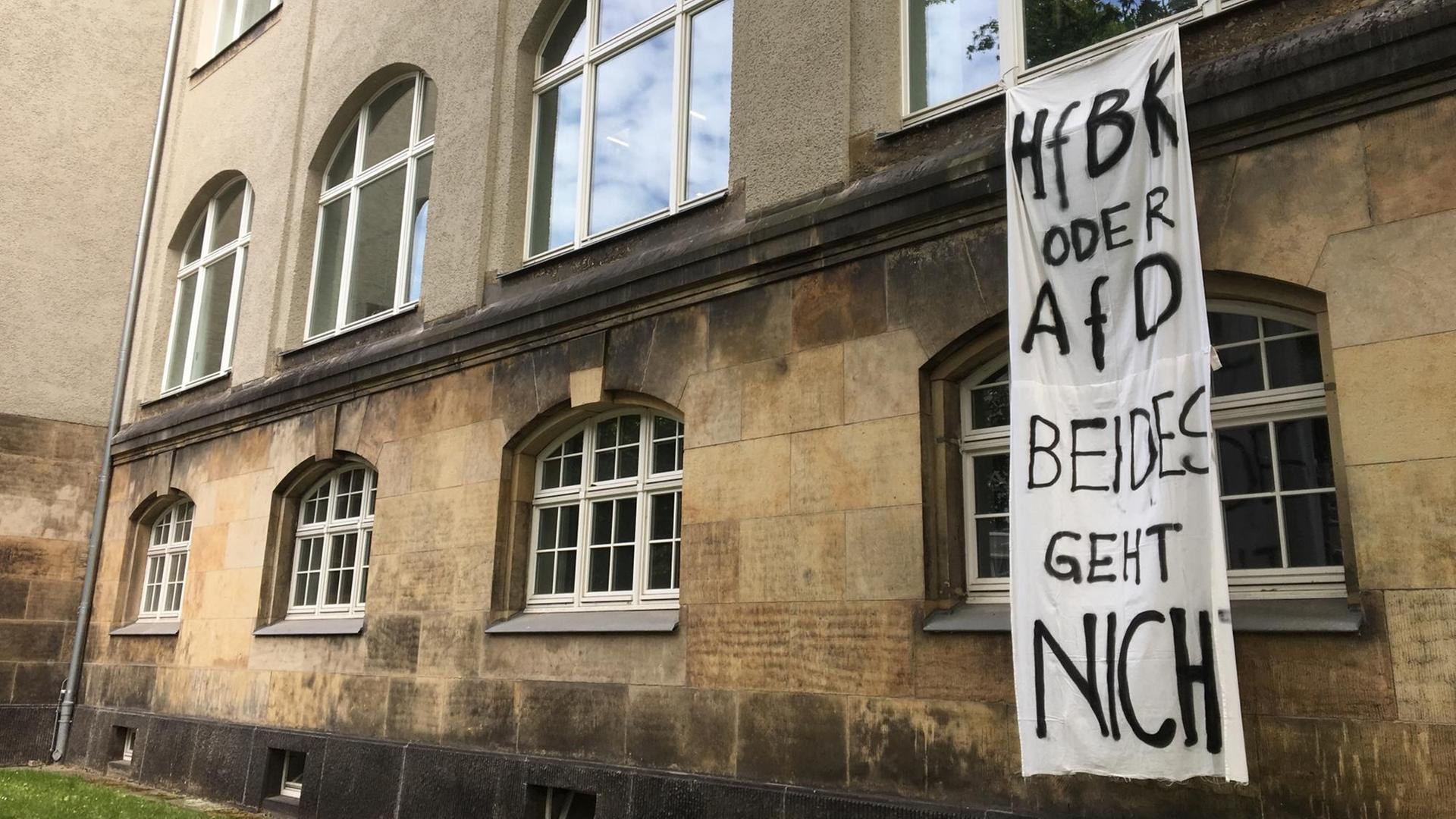 Aus dem ersten Stock des Bibliotheksgebäudes der HfBK Dresden hängt ein weißes Stoffbanner, auf das in schwarzer Schrift steht: "HfBK oder AfD - beides geht nicht". Aus dem ersten Stock des Bibliotheksgebäudes der HfBK Dresden hängt ein weißes Stoffbanner, auf das in schwarzer Schrift steht: "HfBK oder AfD - beides geht nicht".