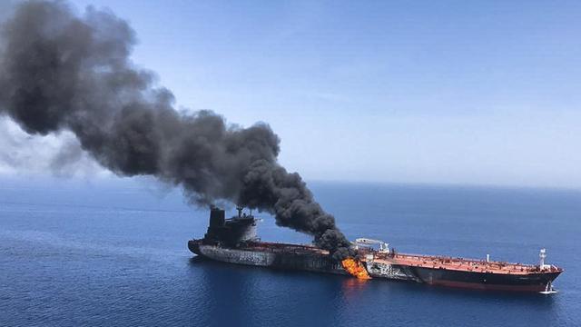 Blick aus der Luft auf den Tanker, an dessen Seite sich ein großer Brand gebildet hat. Dichter schwarzer Rauch steigt auf.