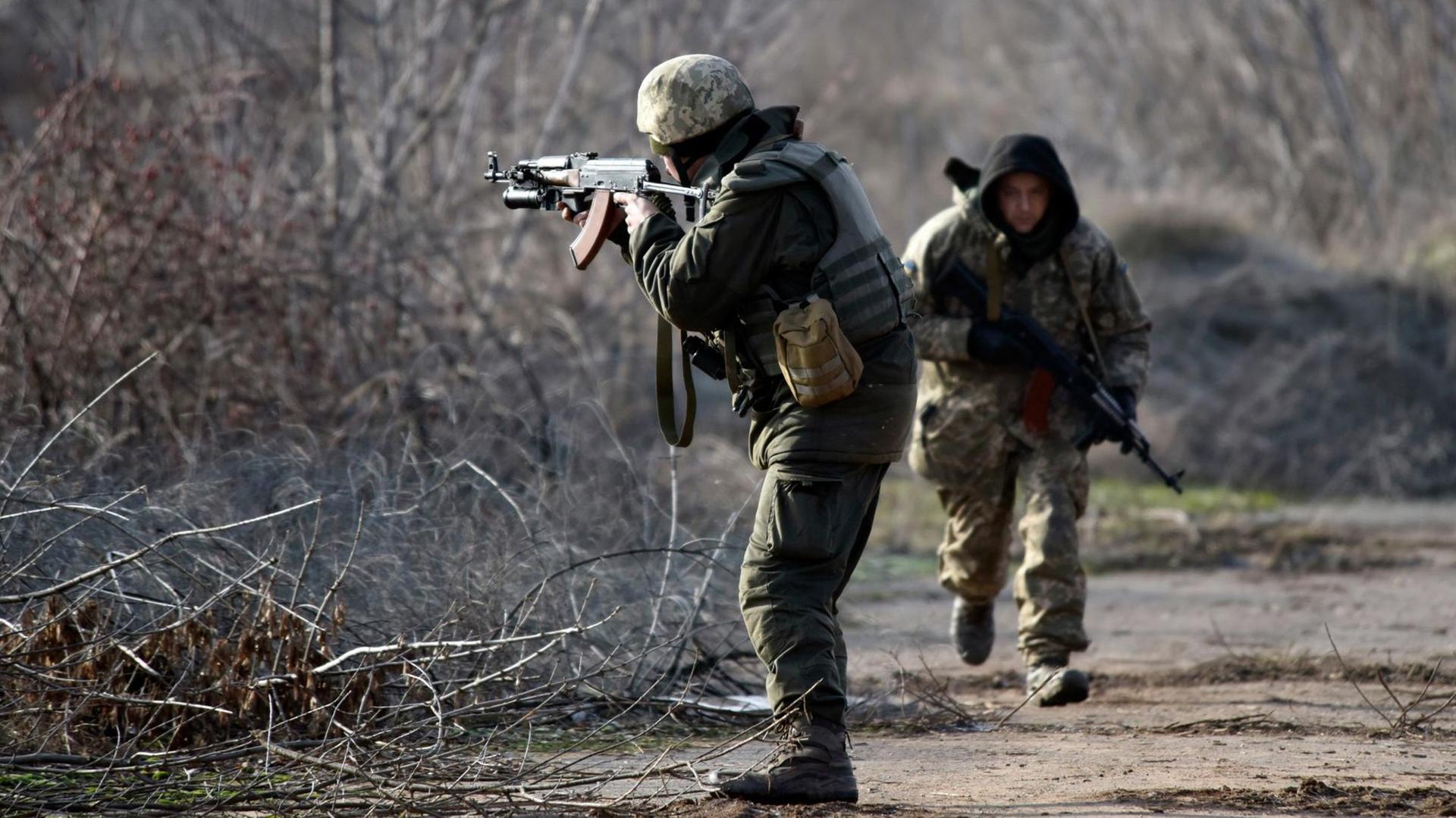 Soldaten der ukrainischen Arme laufen am 11.01.2018 in der Nähe von Nowoluhanske (Ukraine) in der Oblast Donezk an der Frontlinie eine Straße entlang, um ankommenden Journalisten Schutz zu gebieten. Soldaten der ukrainischen Arme laufen am 11.01.2018 in der Nähe von Nowoluhanske (Ukraine) in der Oblast Donezk an der Frontlinie eine Straße entlang, um ankommenden Journalisten Schutz zu gebieten.