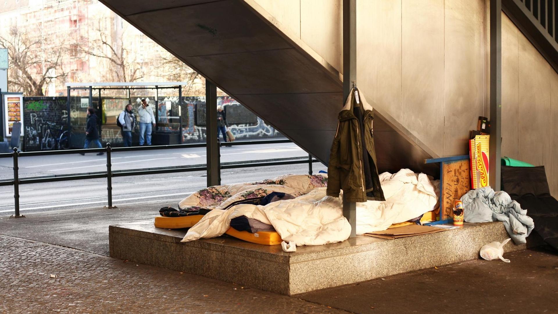 Obdachlose haben zwischen zwei Straßen unter einer Treppe ihr Lager errichtet.
