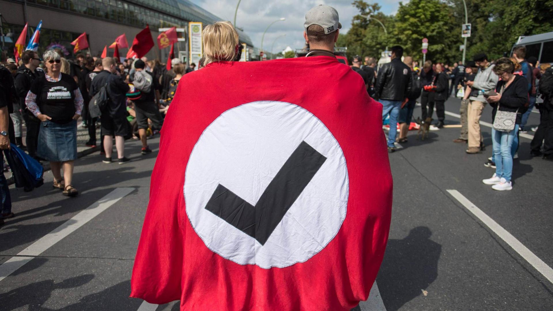 Zwei Demonstranten tragen das Logo von "Hooligans Gegen Satzbau" bei einer Demo gegen den rechtsextremen Hess-Gedenkmarsch in Berlin.