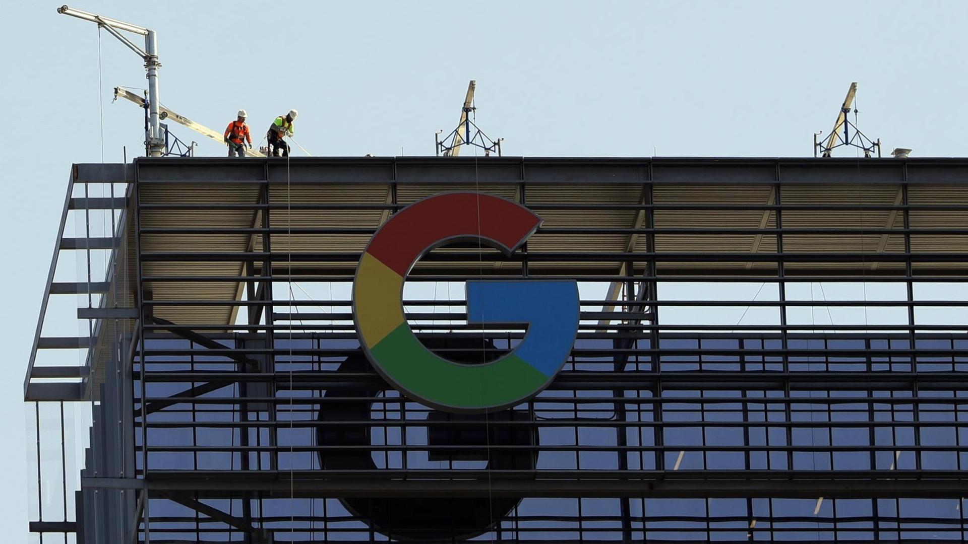 Bauarbeiter arbeiten auf einem Gebäude, an dem das große "G" für Google steht Bauarbeiter arbeiten auf einem Gebäude, an dem das große "G" für Google steht