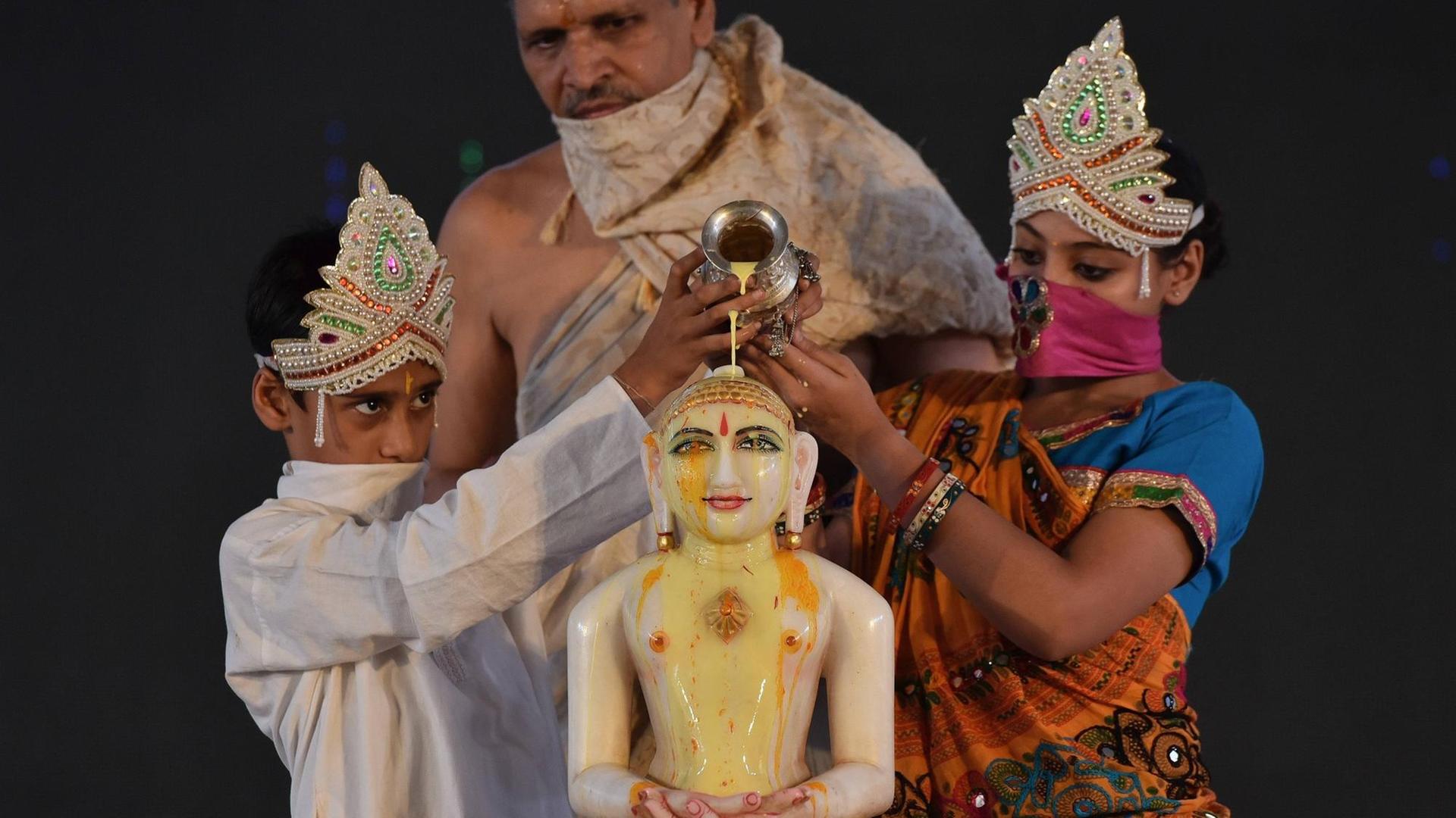 Anlässlich des Festes Mahavir Jayanti, der Feier des Geburtstags von Mahavira, dem 24. und letzten Jina, führen ein Mädchen und ein Junge ein Ritual durch. Anlässlich des Festes Mahavir Jayanti, der Feier des Geburtstags von Mahavira, dem 24. und letzten Jina, führen ein Mädchen und ein Junge ein Ritual durch.