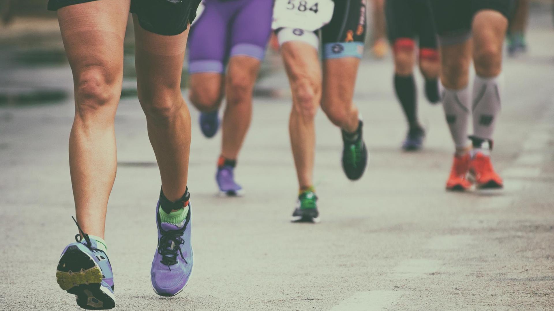 Die Beine einer Gruppe von Marathon-Läufern auf der Straße Die Beine einer Gruppe von Marathon-Läufern auf der Straße