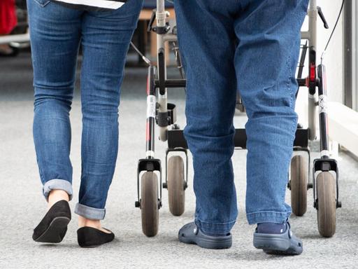 Eine Pflegerin begleitet eine Bewohnerin mit Rollator.