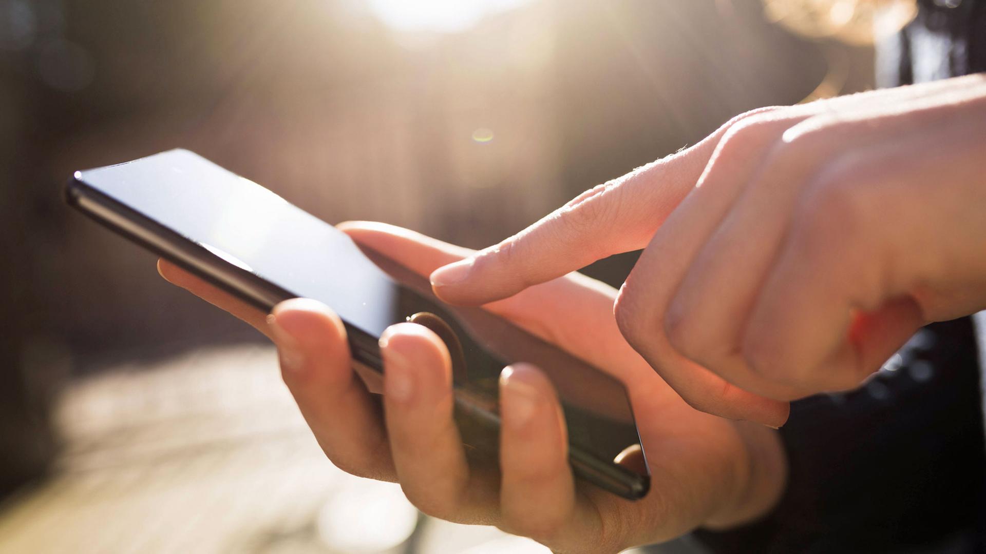 Eine Frau berührt mit dem Zeigefinger den Touchscreen ihres Smartphones. Eine Frau berührt mit dem Zeigefinger den Touchscreen ihres Smartphones.