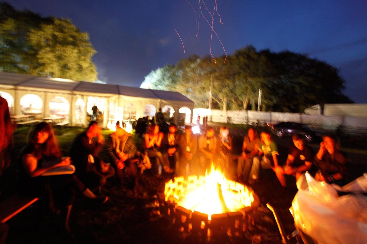 Menschen sitzen um ein großes Lagerfeuer beim Haldern Pop Festival